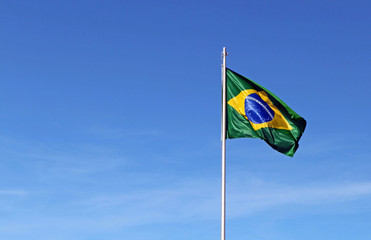Brazil, Brasilia. The flag of Brazil waves against a blue sky.