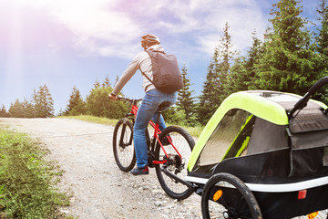 Father With Child In Trailer Riding Mountain Bike