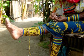 Central America, Panama, San Blas Islands (aka Kuna Yala). Kuna woman in traditional attire working...