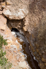 South America - Peru. Salt water spring emerges from hillside and runs down to salt ponds near Maras where the salt water evaporates and salt is extracted for sale at markets.