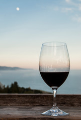 USA, California, Big Sur, Nepenthe restaurant, view of Lucia Mountains, Pacific Ocean, glass of red wine and full moon