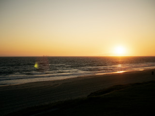 sunset with lens flare and beach in silhouette.