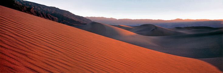 USA, California, Death Valley NP. Evening light forms long shadows on this sand dune in Death...