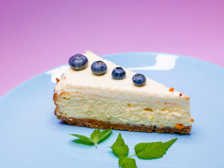 Blueberry Cheesecake. Blueberry mint cheesecake on a pink, purple, coral background. on a blue plate. Tasty breakfast. side view