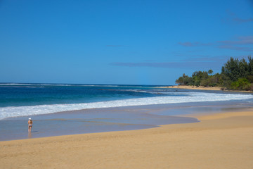 Woman walking on sand at Ke'e Beach at Ha'ena State Park on Northshore of Kauai, Hawaii