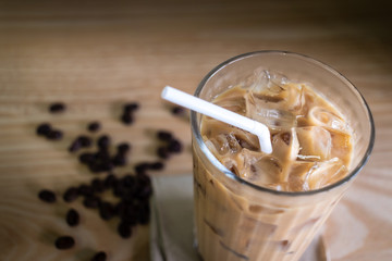 Cold brewed iced coffee in glass and coffee beans on wood table
