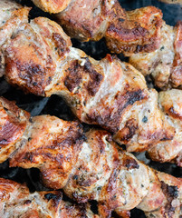 Frying pork on a skewer over a brazier. Turning meat over coals. Appetizing shish kebab.