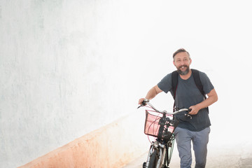 hipster man with a backpack pushing a retro bicycle