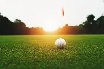 Fotobehang golf ball on green grass with hole and sunlight © lovelyday12