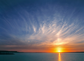 USA, North Dakota, Lake Sakakawea. Cirrus clouds take on the colors of the sun setting over Lake...
