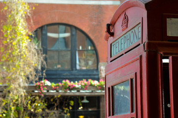 Fototapeta na wymiar Red traditional British phone booth, building facades in Old Market historic district in downtown Omaha, Nebraska