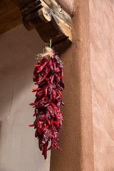 Santa Fe, New Mexico. Long, red chili, hanging from a wooden corbel and stucco wall