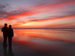 Fototapeta na wymiar USA, Oregon, Cannon Beach. Couple contemplates the sunset. (MR)
