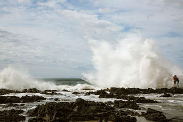 Fototapeta na wymiar USA, Oregon, Cape Perpetua. Two girls near large crashing wave. 
