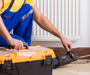 Fototapeta premium Young repairman contractor repairing heating panel