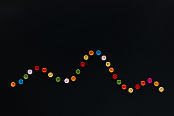A wave made from buttons on a black background , shot from above.