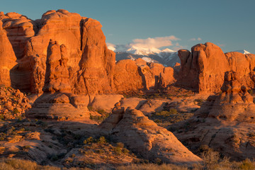 USA, Utah. Red rock formations and snow on the La Sal Mountains at sunset