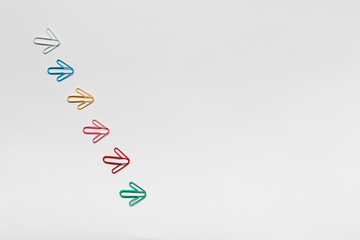 Many arrows on white background, shot from above, aligned from top left towards bottom right.