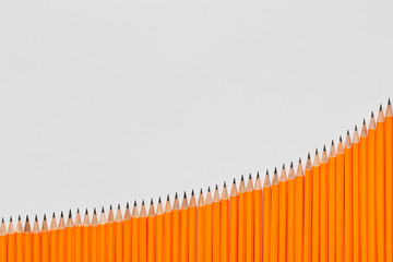 A bunch of pencils aligned in an ascending order on white background, shot from above, closeup.