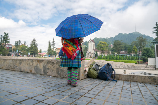 Ethnic minority Hmong woman with her child on back in beautiful costume dress in Sapa, Vietnam