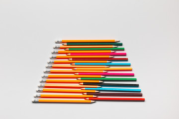 A pattern made with pencils and wooden crayons on white background, shot from above.