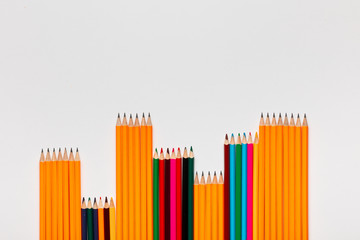 A pattern made with pencils and wooden crayons on white background, shot from above.