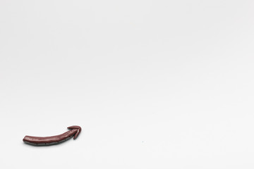 An arrow pointing upwards made from chalk on white background, shot from above.