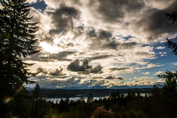 Bremerton, Washington State. Sunburst breaks through silver clouds and patches of blue sky over the...
