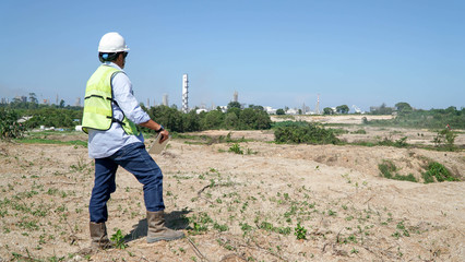 rear view of male engineer walking and holding tablet computer on bright blue sky for planing a construction
