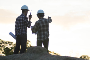 Naklejka premium Blurry silhouette portrait of two engineers or architects pointing at the golden sky