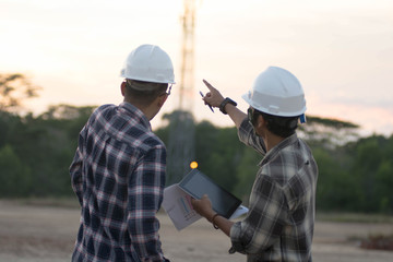 portrait of two engineer's or architect's dress with hardhat, safety helmet meeting outdoors at sunrise or sunset