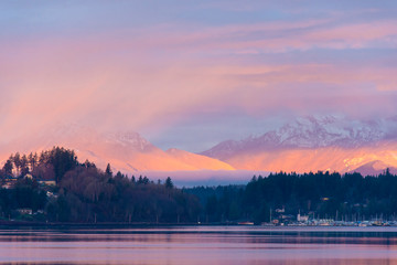 US, Washington State, Kitsap Peninsula. Dramatic pink sunrise patterns through cloud layers over Olympic Mountains