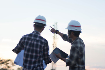 portrait of two engineer's or architect's dress with hardhat, safety helmet meeting outdoors at sunrise or sunset