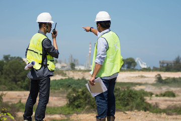 portrait of two engineer's or architect's dress with hardhat safety helmet and safety vest have a meeting and pointing to new construction sites at outdoor