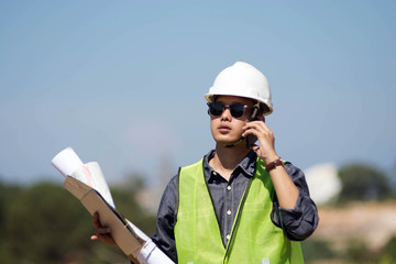 portrait of bussy young handsome architect or engineer supervisor talking on cell phone outdoors with clear blue sky