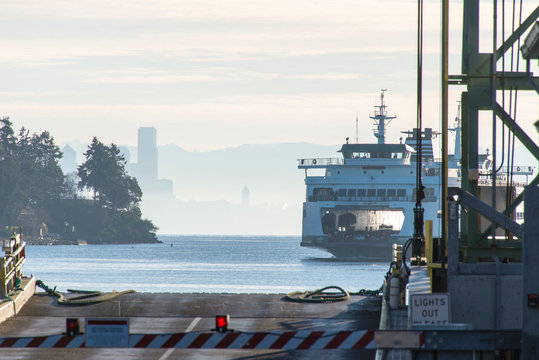 US, Washington State, Seattle ferry arrives Bainbridge with first load of bicyclists for Chilly Hilly race. Seattle skyline in morning fog