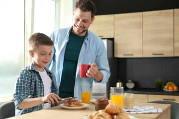 Fototapeta na wymiar Dad and son having breakfast together in kitchen
