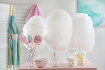Tasty cotton candy and other sweets on table in room