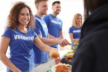 Volunteers serving food to poor people indoors