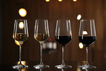 Glasses of different wines on table against blurred background