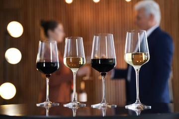 Glasses of different wines on table against blurred background