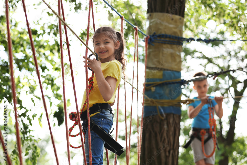 Poster Little girl climbing in adventure park. Summer camp