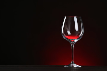 Empty wine glass on table against dark background, space for text