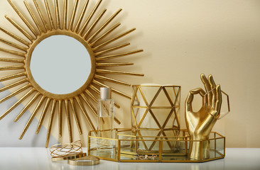 Composition with golden accessories and jewelry on dressing table near color wall
