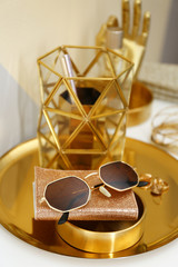 Gold tray with notebook, glasses and accessories on dressing table