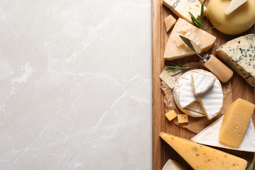Different delicious cheeses served on grey table, top view. Space for text