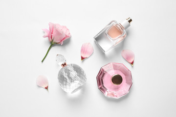 Different perfume bottles and flowers on white background, top view - obrazy, fototapety, plakaty