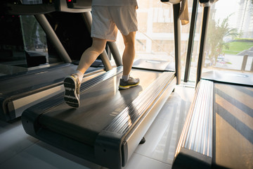 Fototapeta na wymiar Machine treadmill with people running closeup at fitness gym