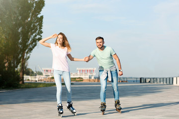 Obraz premium Young happy couple roller skating on city street