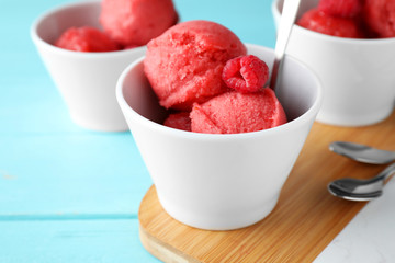 Bowl with delicious raspberry ice cream on light blue wooden table, closeup
